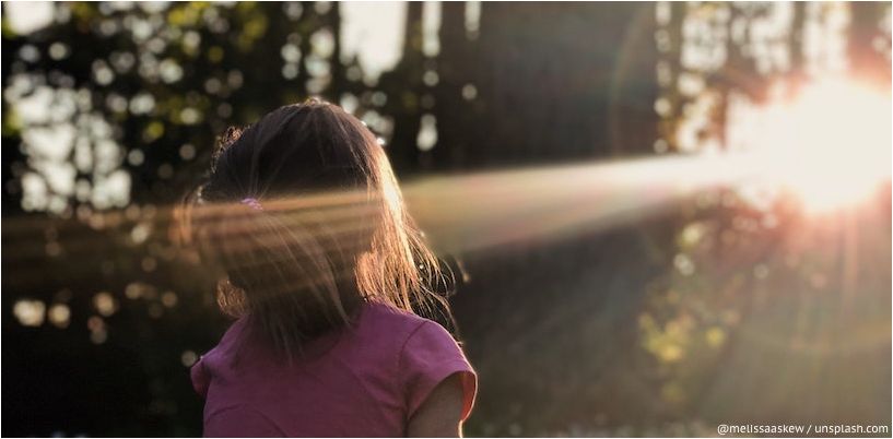 fata se uită la o rază de soare în pădure