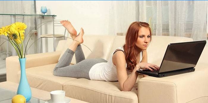 Fata se află pe o canapea cu laptop