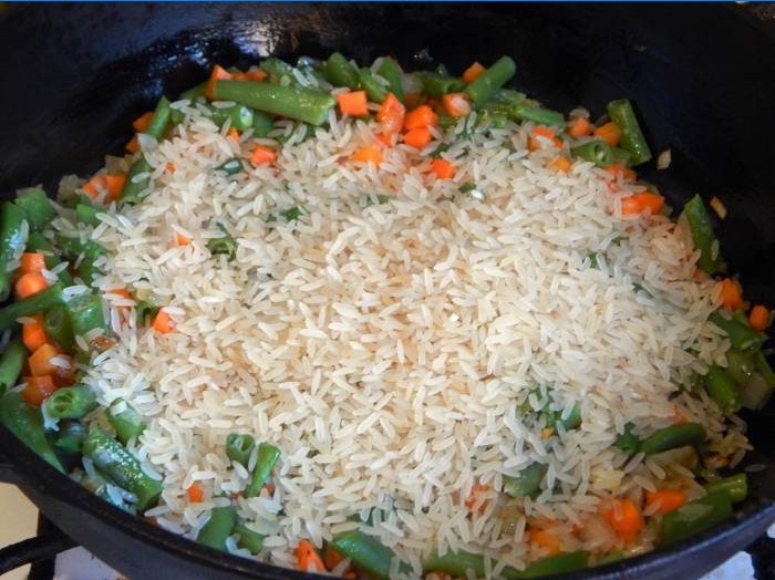 Adăugați orez într-o tigaie cu legume