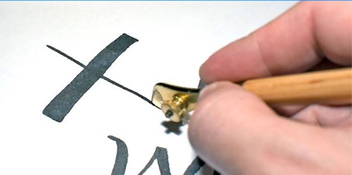 Omul desenează un hieroglif folosind un stilou de desen