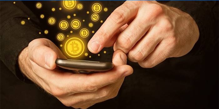 Bărbat cu smartphone în mâini și icoane bitcoin.