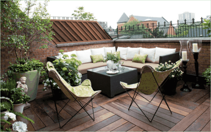 Designul terasei casei de țară de pe acoperiș - o canapea de colț, fotolii și flori
